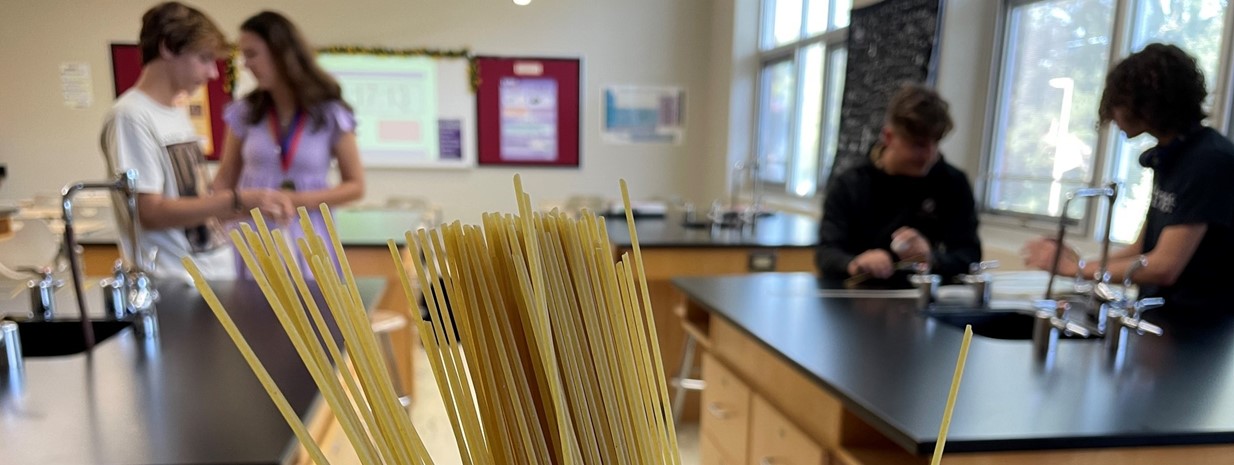 Physics students work to construct a spaghetti tower to hold a marshmallow